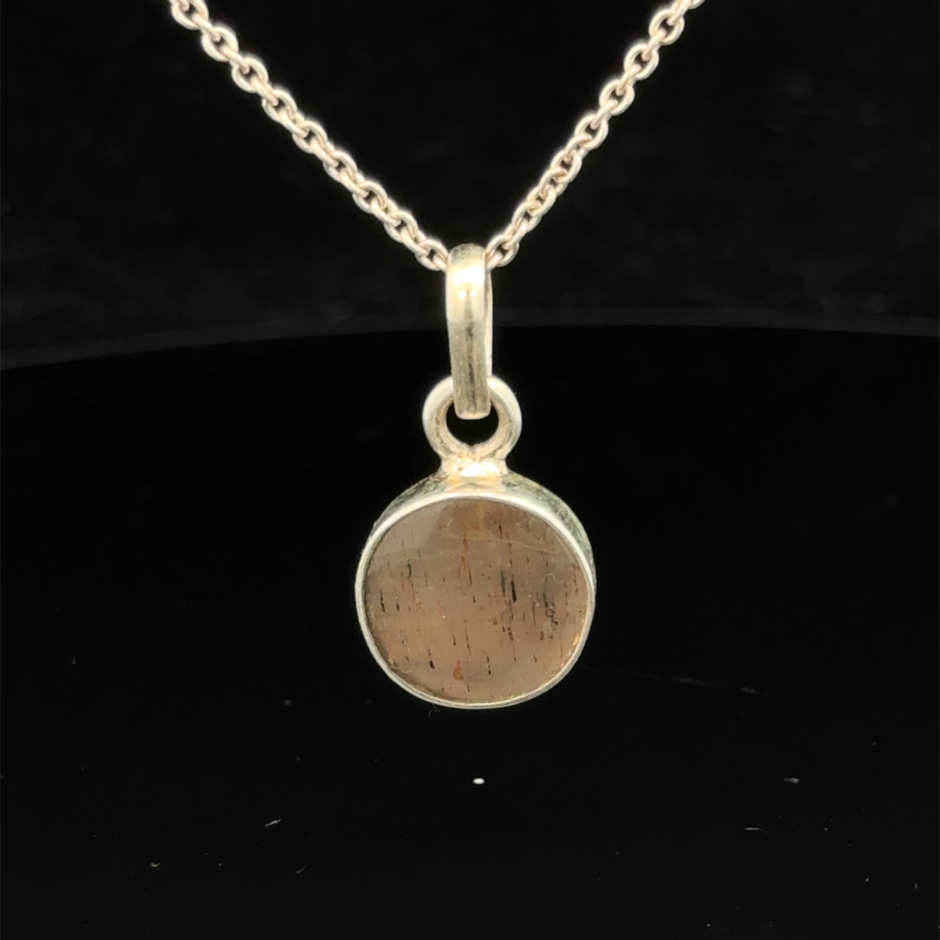 Brown Confetti Moonstone Sunstone pendant set in sterling silver bezel on a black background, hung, front view. 