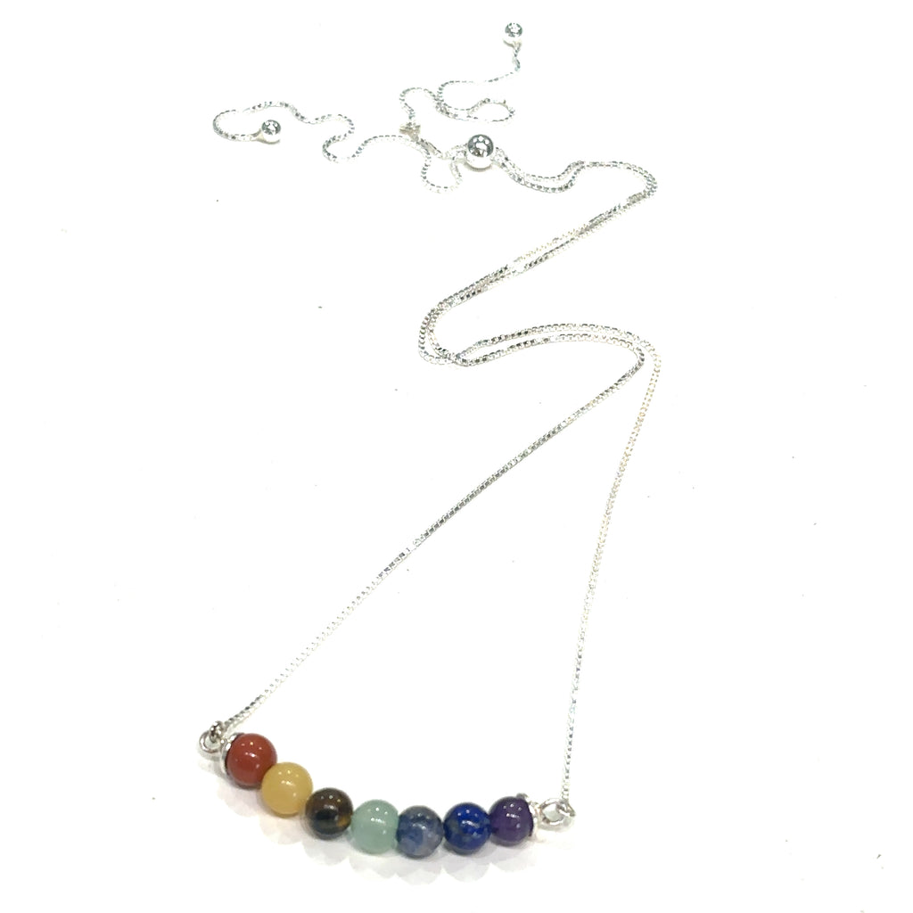 Chakra balancing necklace with amethyst, lapis lazuli, sodalite, aventurine, jade, tiger eye, red jasper on white hanging front overview