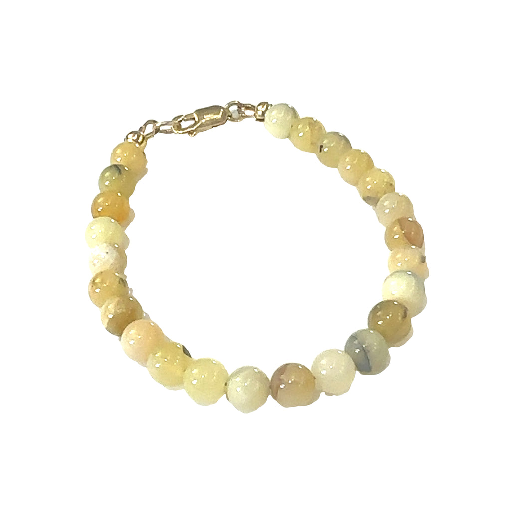 Close-up of 6mm smooth Yellow Opal beads showing natural yellow tones on a white background, front side view