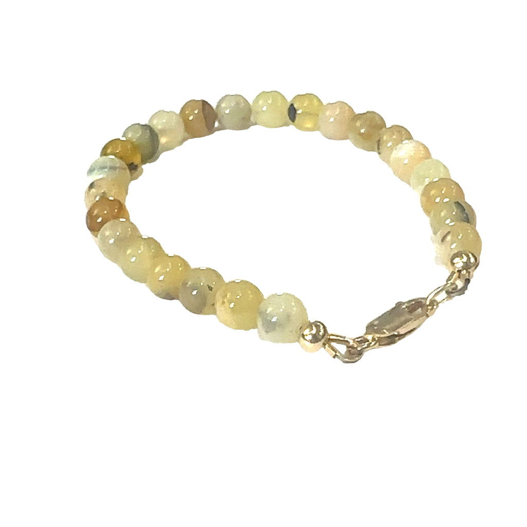 Close-up of 6mm smooth Yellow Opal beads showing natural yellow tones on a white background, left side back view