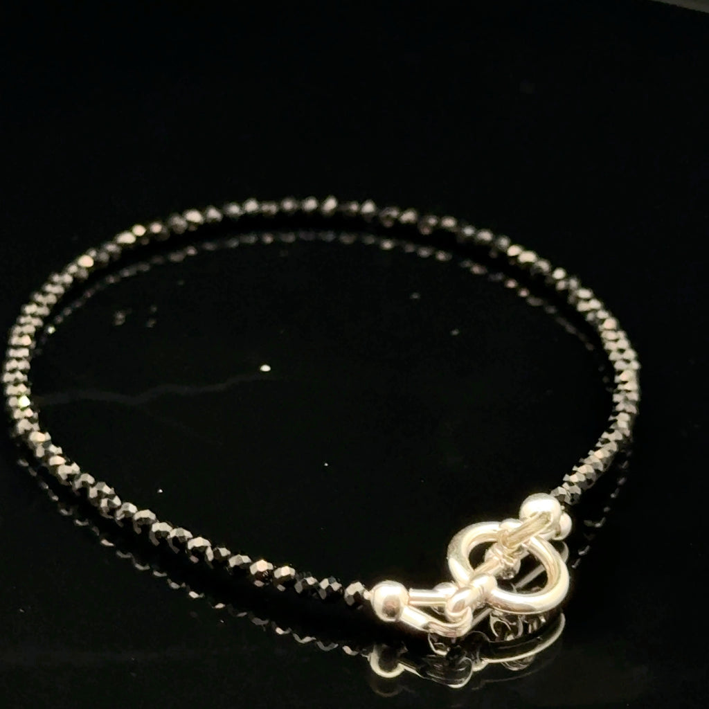 Close-up of Black Spinel beads showing deep black color and brilliant luster, gemstone-quality bracelet for power and protection, on a black background, back side view.