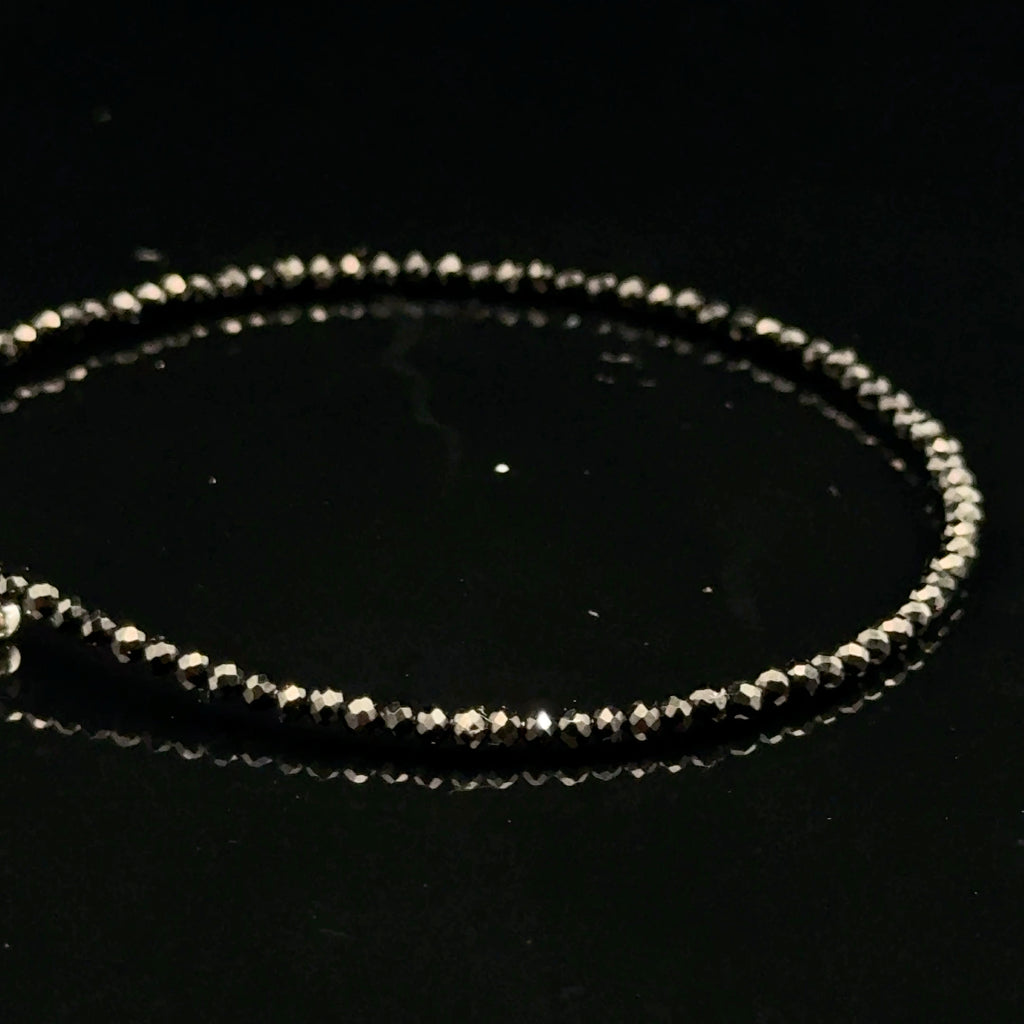 Close-up of Black Spinel beads showing deep black color and brilliant luster, gemstone-quality bracelet for power and protection, on a black background, left side view.