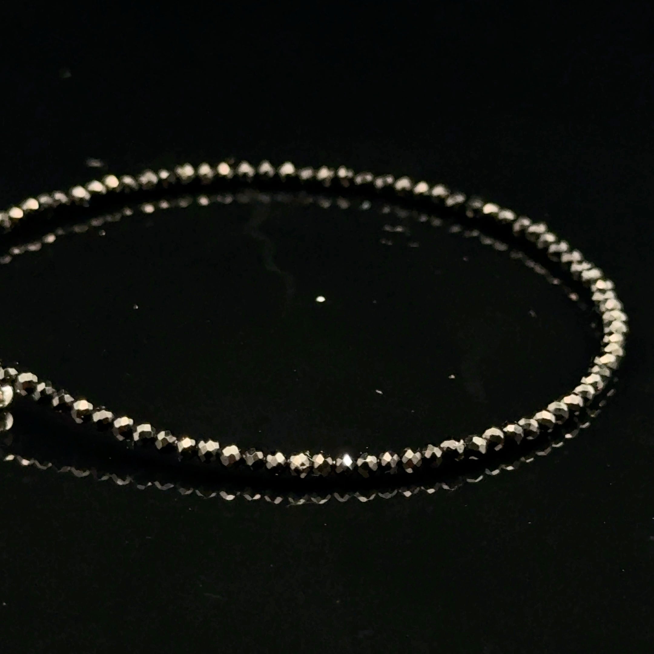 Close-up of Black Spinel beads showing deep black color and brilliant luster, gemstone-quality bracelet for power and protection, on a black background, left side view.