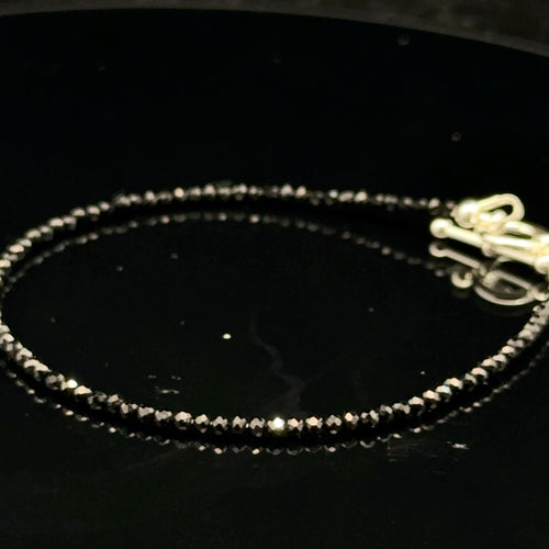 Close-up of Black Spinel beads showing deep black color and brilliant luster, gemstone-quality bracelet for power and protection, on a black background, right side view.