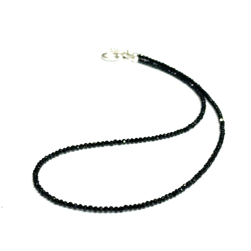 Close-up of Black Spinel beads showing deep black color and brilliant luster, gemstone-quality necklace for power and protection, on a white background, front close-up overview. 