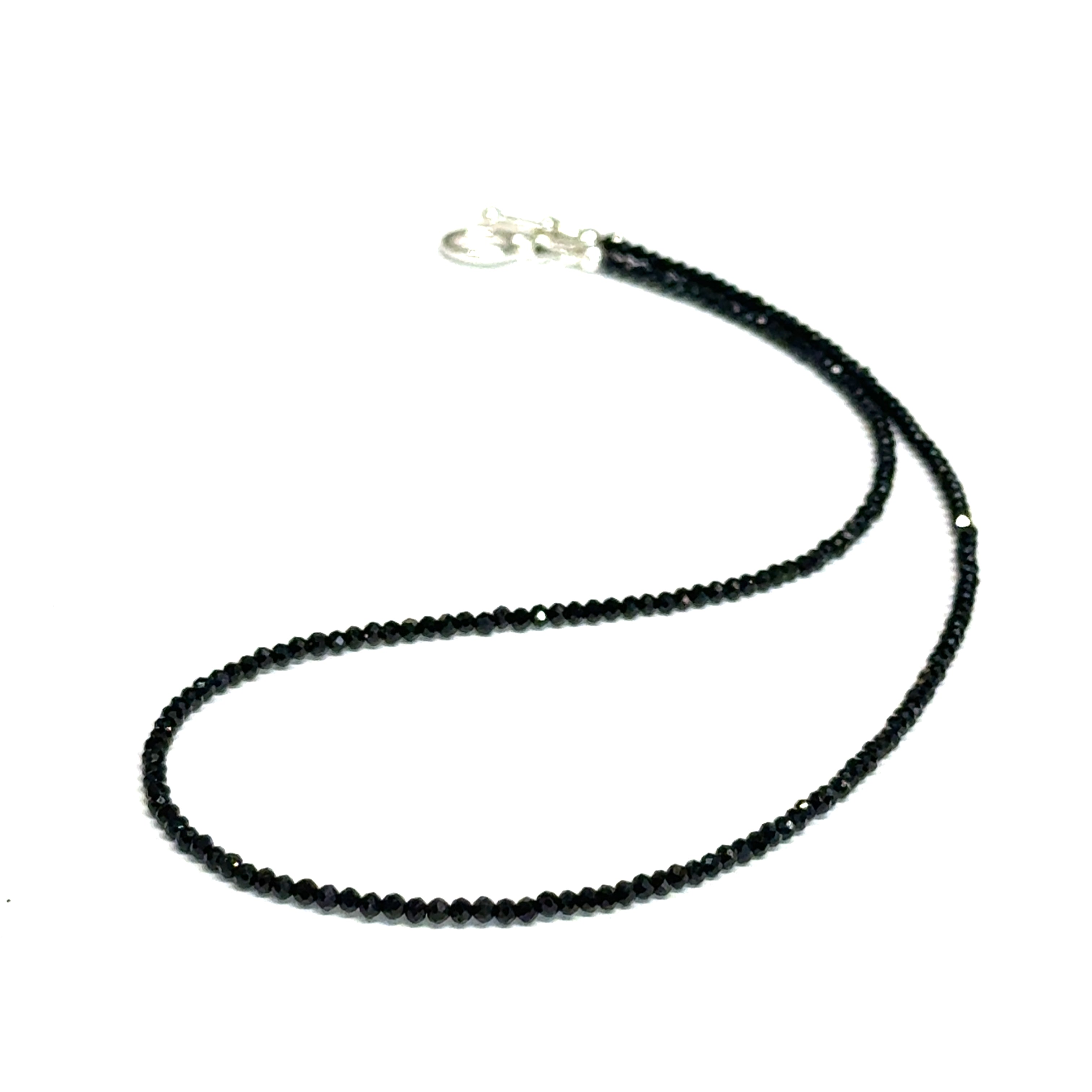 Close-up of Black Spinel beads showing deep black color and brilliant luster, gemstone-quality necklace for power and protection, on a white background, front close-up overview. 