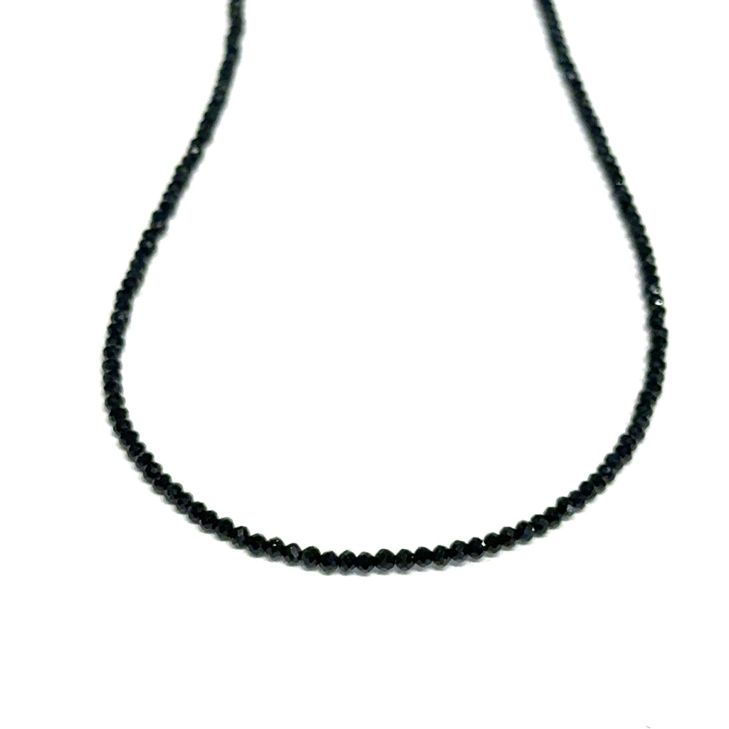 Close-up of Black Spinel beads showing deep black color and brilliant luster, gemstone-quality necklace for power and protection, on a white background, front close up hanging view. 