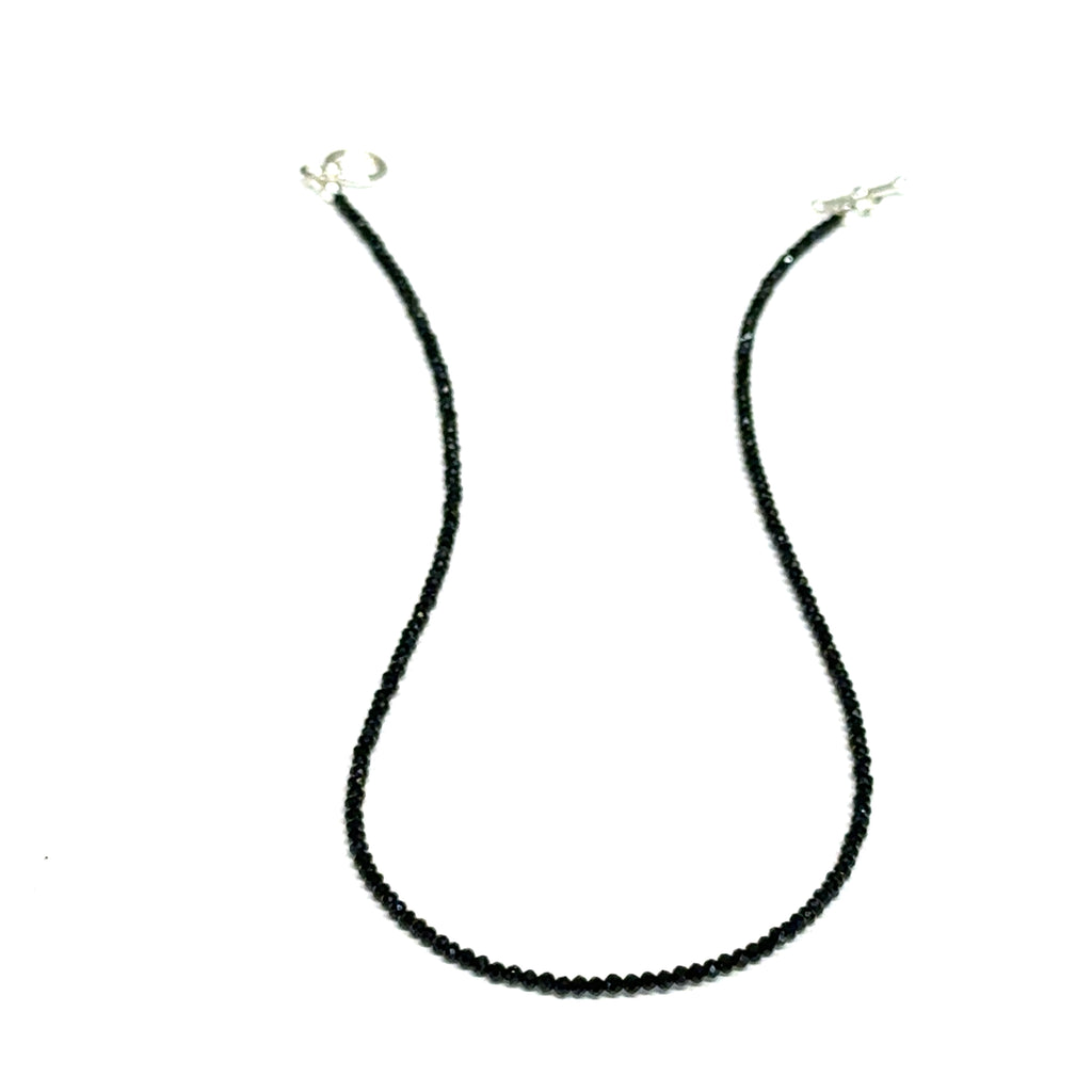 Close-up of Black Spinel beads showing deep black color and brilliant luster, gemstone-quality necklace for power and protection, on a white background, front hanging view. 