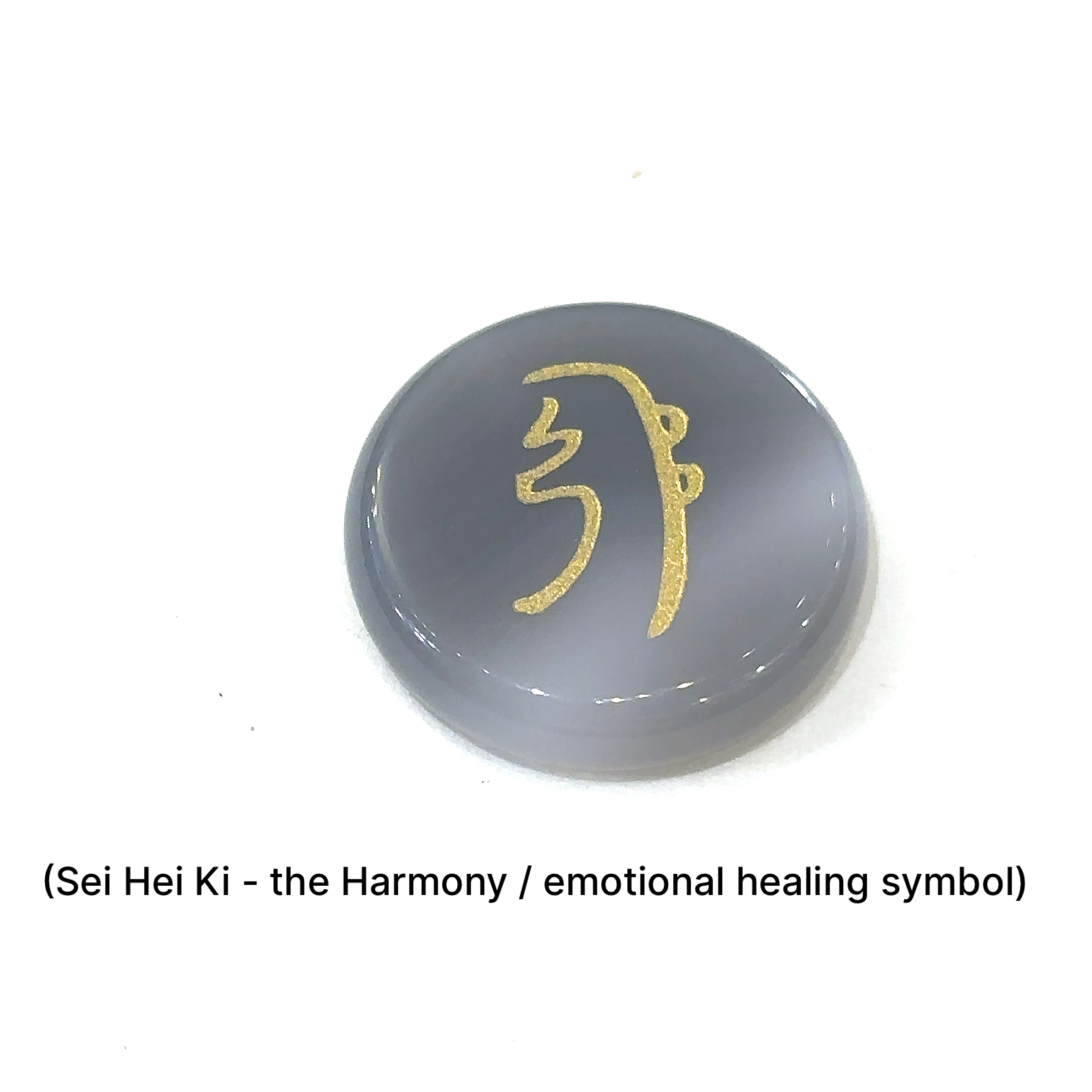 Close-up of Botswana Agate stone showing engravedSei Hei Ki the harmony Symbol in gold on a white background front view. 