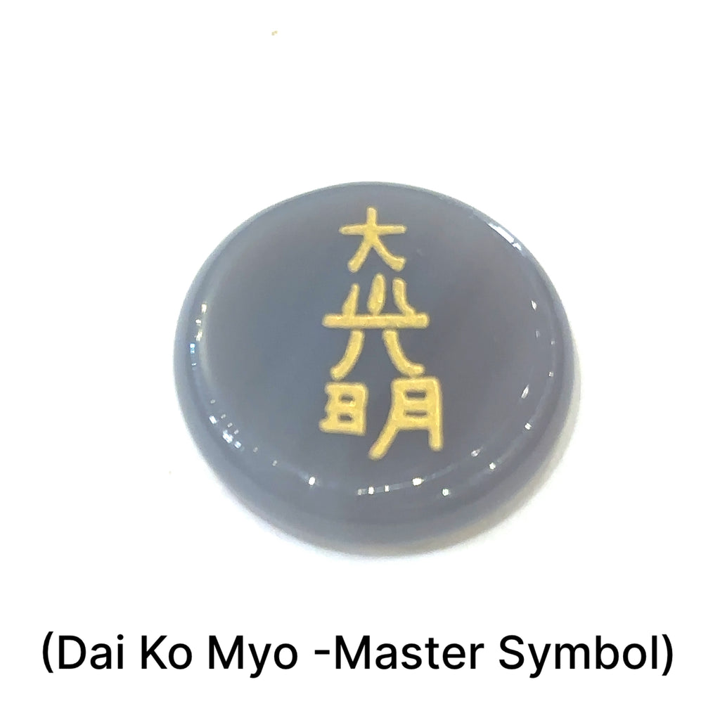 Close-up of Botswana Agate stone showing engraved  Dai Ko Myo the master Symbol in gold on a white background front view. 