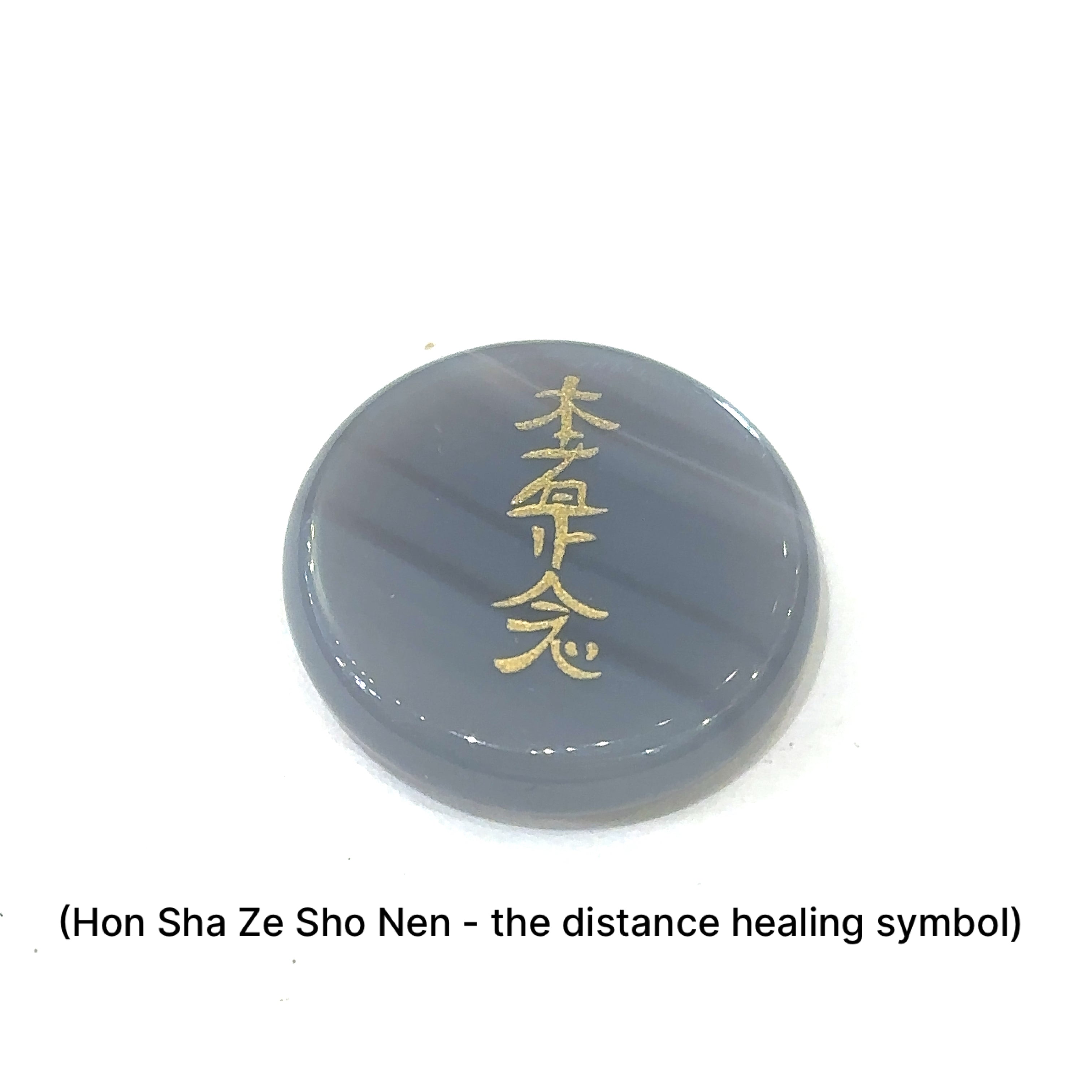 Close-up of Botswana Agate stone showing engraved  Hon Sha Ze Sho Nen the distant healing Symbol in gold on a white background front view. 