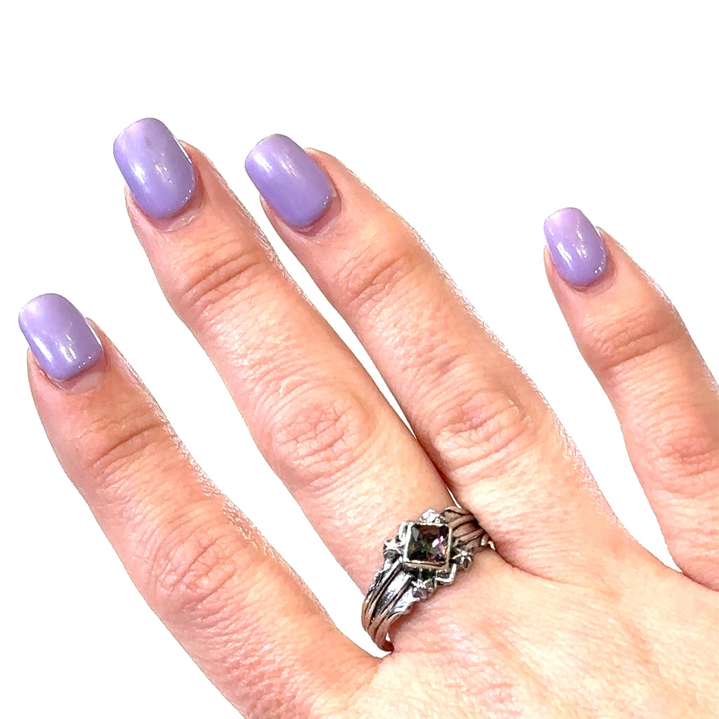 Close-up of Mystic Topaz gemstone showing rainbow iridescence in a square-cut setting modeled on hand on white front view