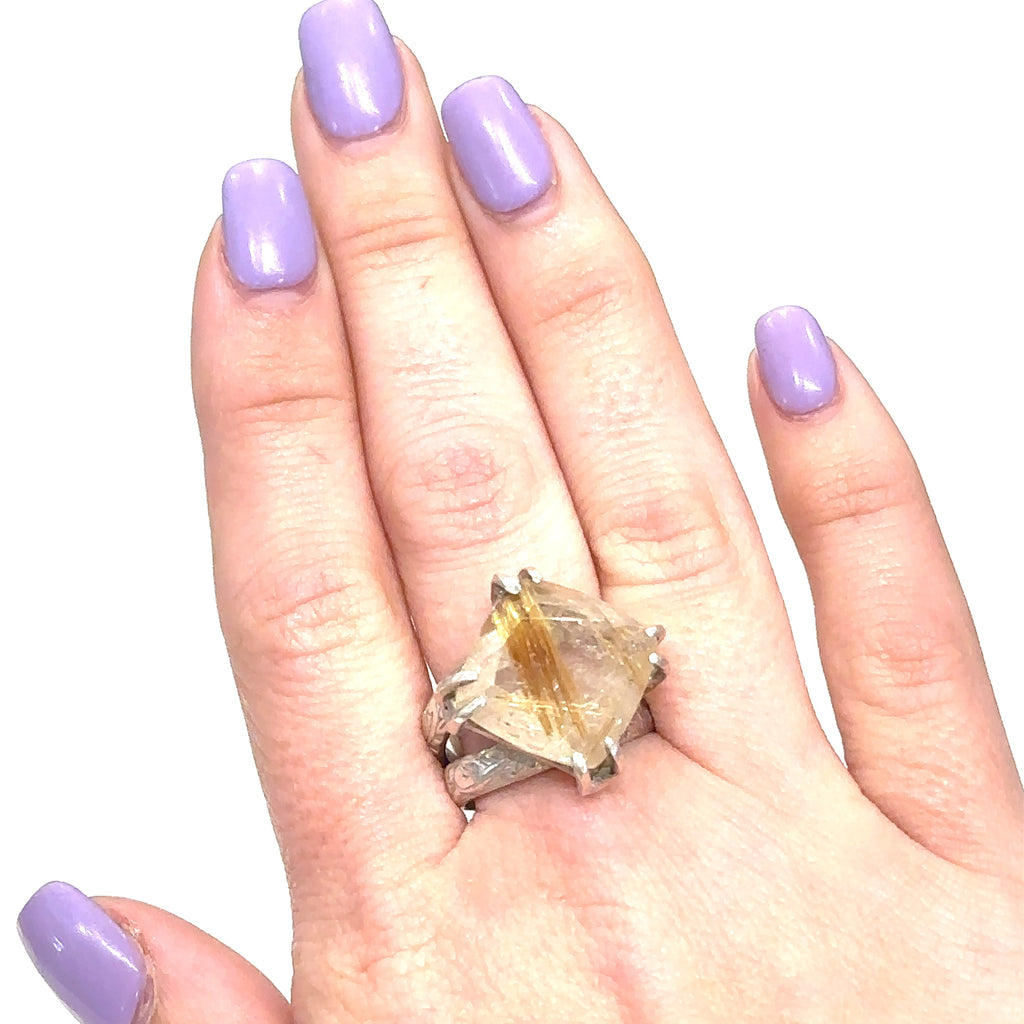 Close-up of Rutilated Quartz showing golden Rutile inclusions within clear quartz on white on finger for close up front  view