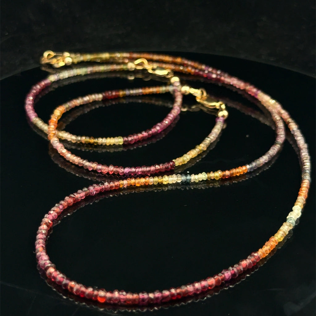 Close-up of both natural brown sapphire beaded bracelet with it matching necklace showing honey amber to chocolate color variations, on a black background, overview.