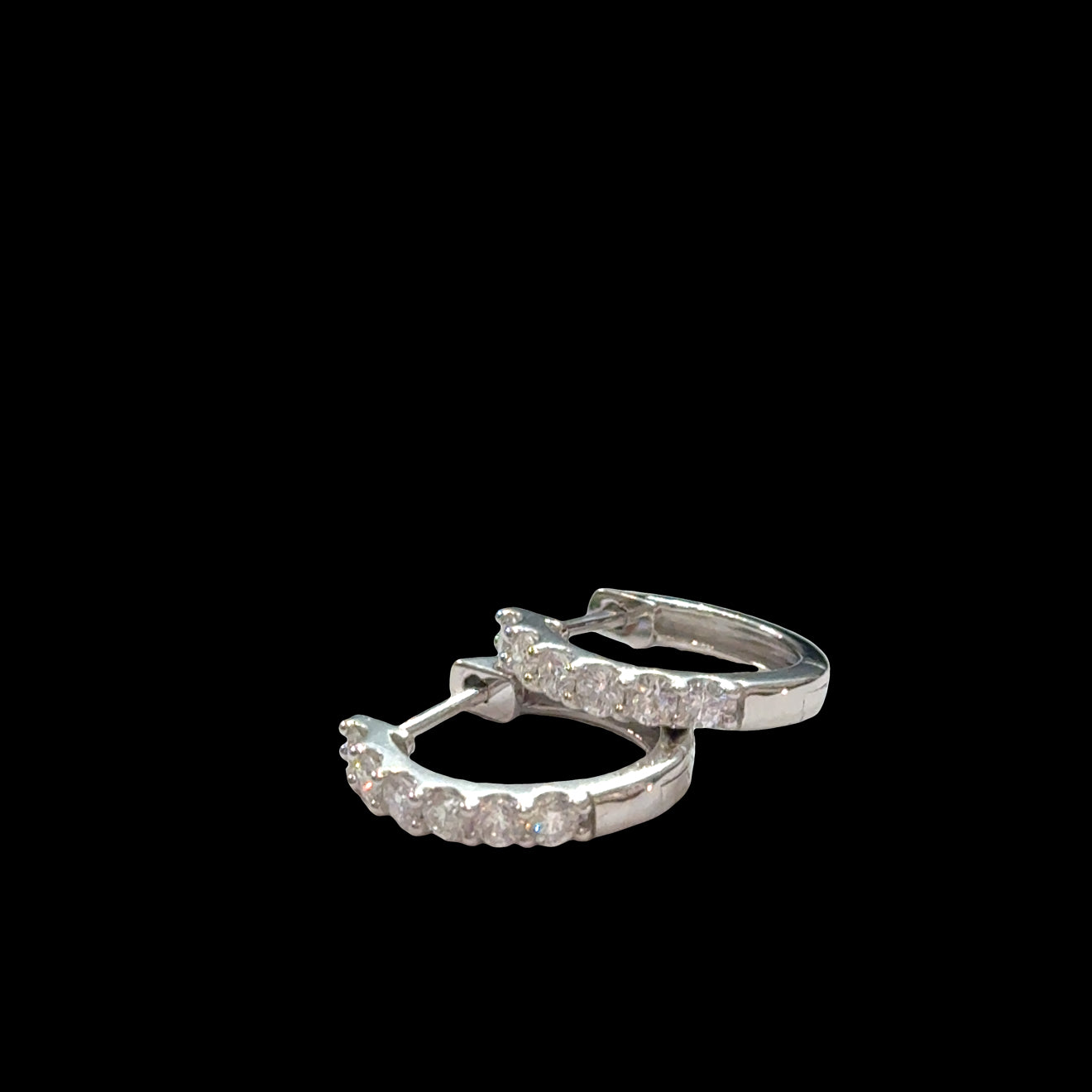 Close-up of diamond huggie hoops 925 silver with secure hinged closure, lab-grown diamonds, hypoallergenic everyday earrings, on a black background, front view.