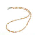 Close-up of faceted pink opal gemstone beads catching light on delicate beaded necklace on a white background, front view.