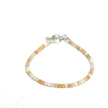 Close-up of faceted pink opal gemstone beads on a delicate beaded bracelet with a handcrafted toggle on a white background, front view. 