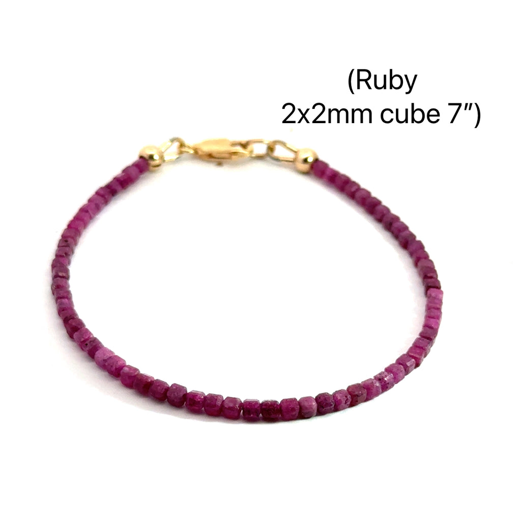 Close-up of faceted ruby cubed beaded bracelets with gold filled lobster claw size 7'', showing deep red hues and natural shine on a white background, front overview.