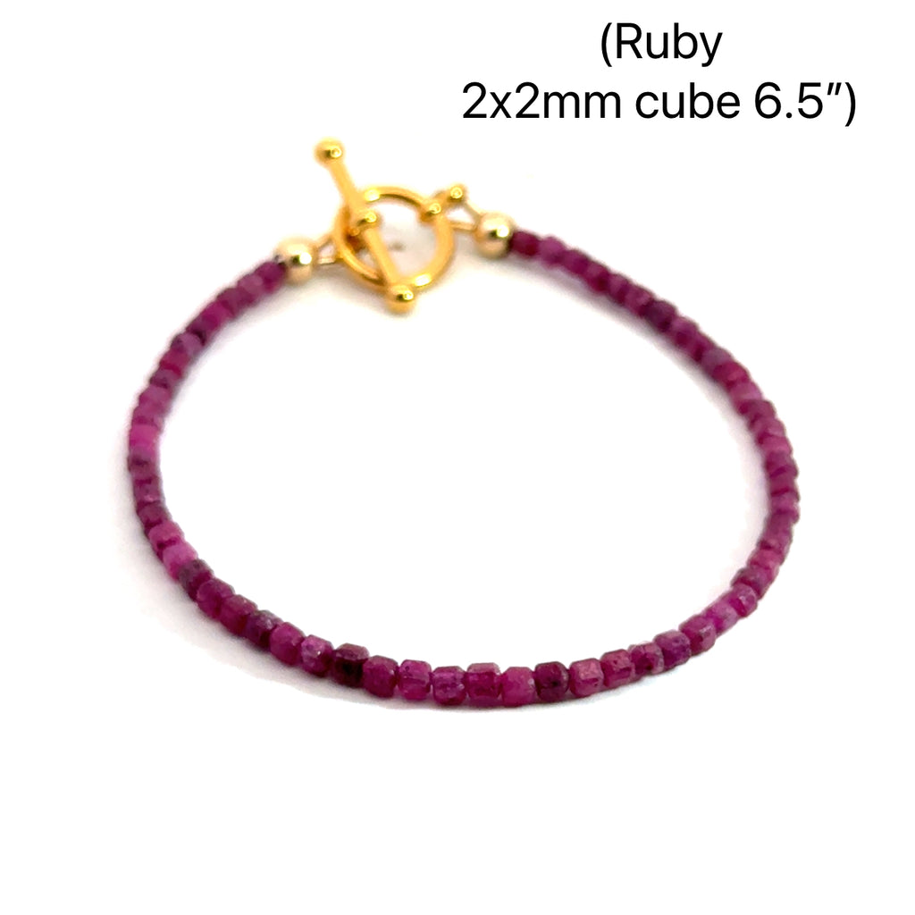 Close-up of faceted ruby cubed beaded bracelets with gold filled toggle size 6.5'', showing deep red hues and natural shine on a white background, front overview.