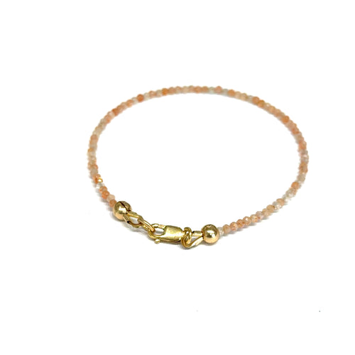 Close-up of faceted sunstone gemstone beads on delicate beaded bracelet with natural shimmer and gold-filled clasp on a white background, back view. 
