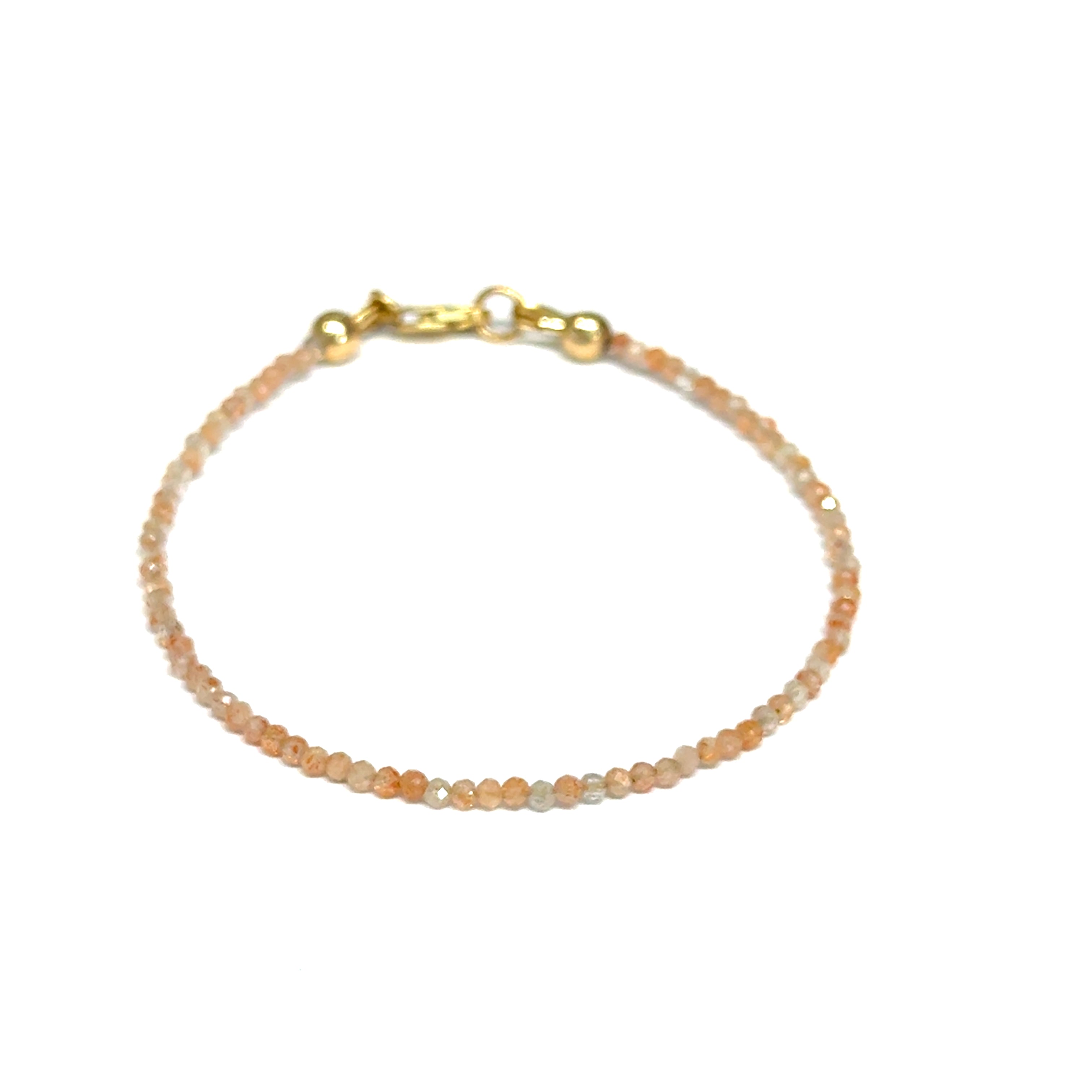Close-up of faceted sunstone gemstone beads on delicate beaded bracelet with natural shimmer and gold-filled clasp on a white background, front view. 