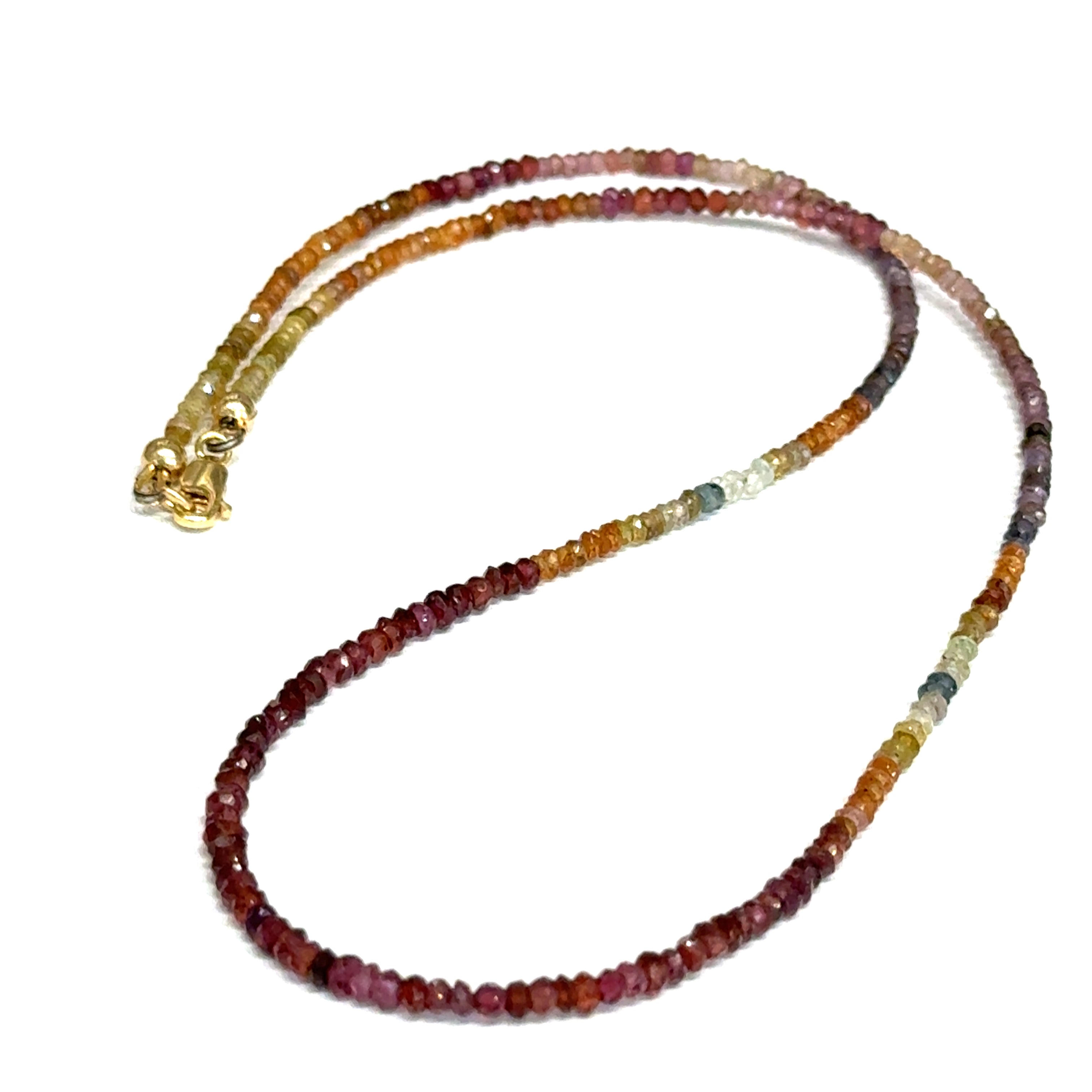 Close-up of natural brown sapphire beads showing honey amber to chocolate color variations, on a white background,  in a long overview. 