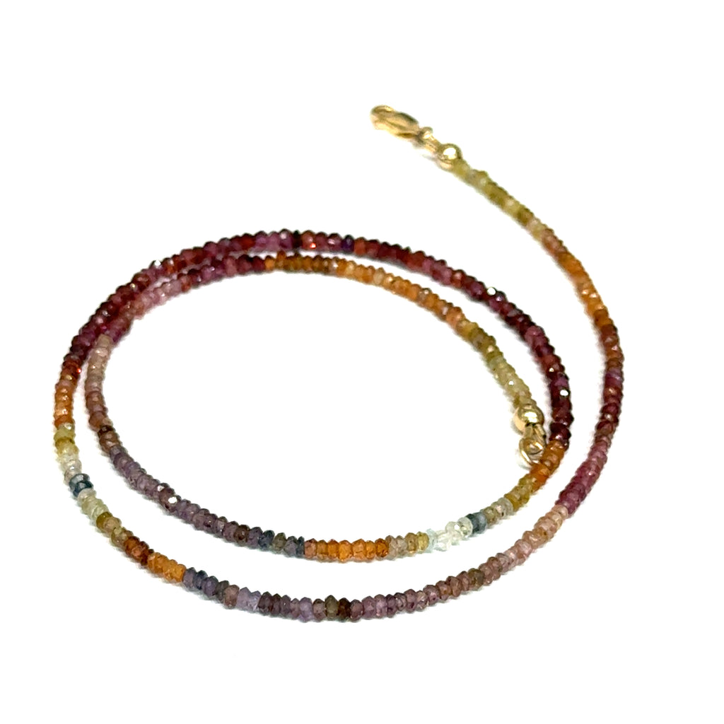 Close-up of natural brown sapphire beads showing honey amber to chocolate color variations, on a white background,  in a spiral front view. 