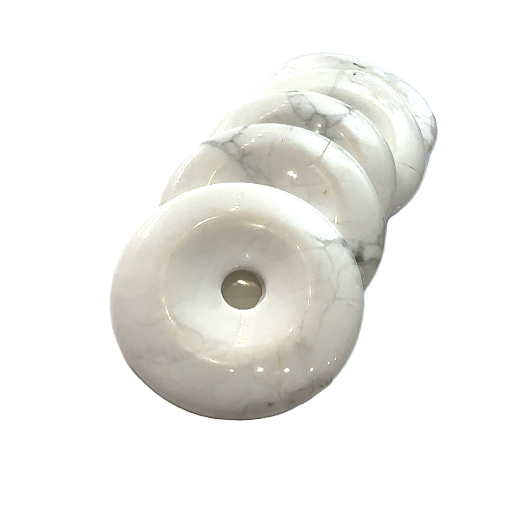 Close-up of polished gemstone donuts showing natural color and pattern variations on several Howlite front overview on white background