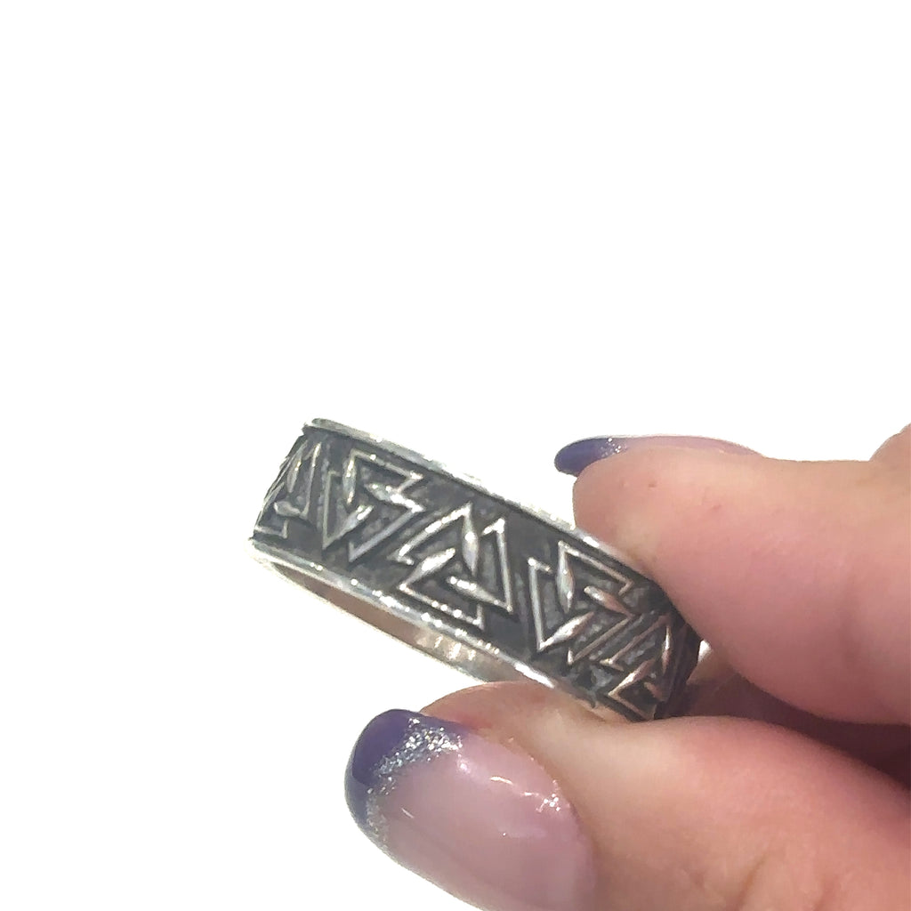 Custom‑designed sterling silver ring with sacred geometry triangle pattern on white in fingers