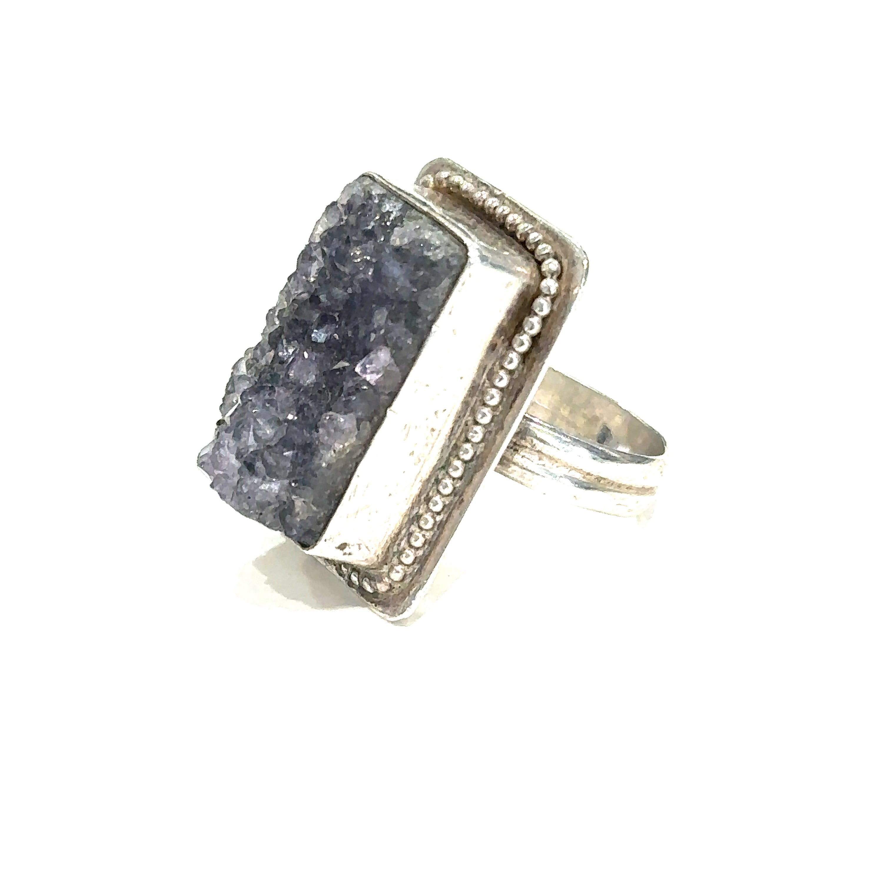 Detailed close-up of natural Amethyst druzy crystal showing purple sparkle and raw texture on white left angle view