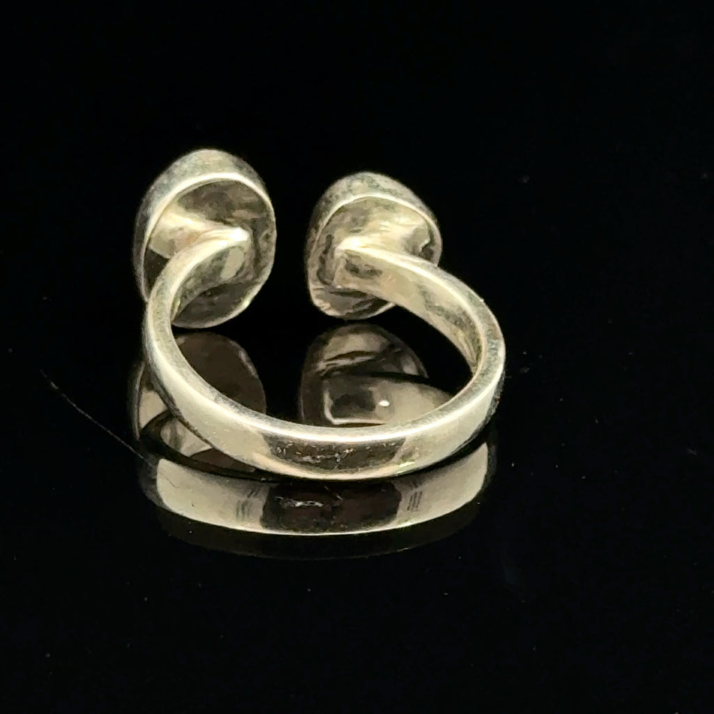 Detailed view of faceted Moldavite and Herkimer Diamond gemstones bezel-set in sterling silver, showing radiant green and clear crystal brilliance on a black background back of the ring view. 