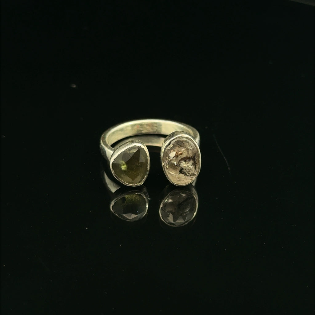 Detailed view of faceted Moldavite and Herkimer Diamond gemstones bezel-set in sterling silver, showing radiant green and clear crystal brilliance on a black background front center view. 