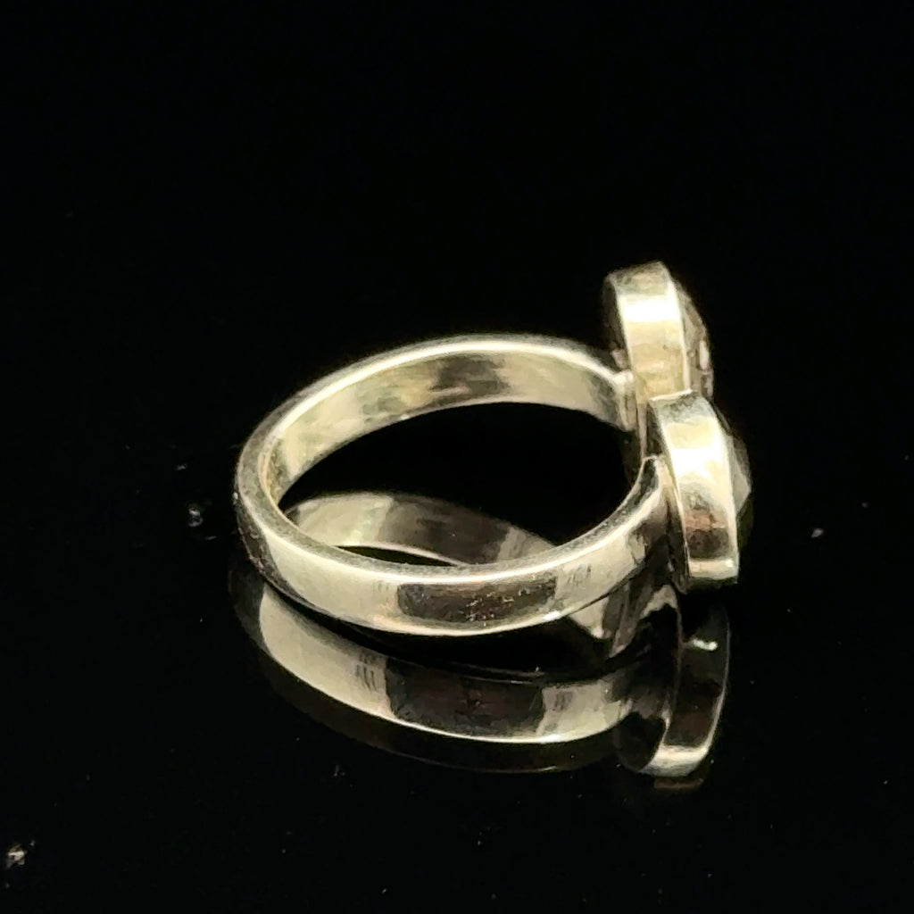 Detailed view of faceted Moldavite and Herkimer Diamond gemstones bezel-set in sterling silver, showing radiant green and clear crystal brilliance on a black background right side view. 