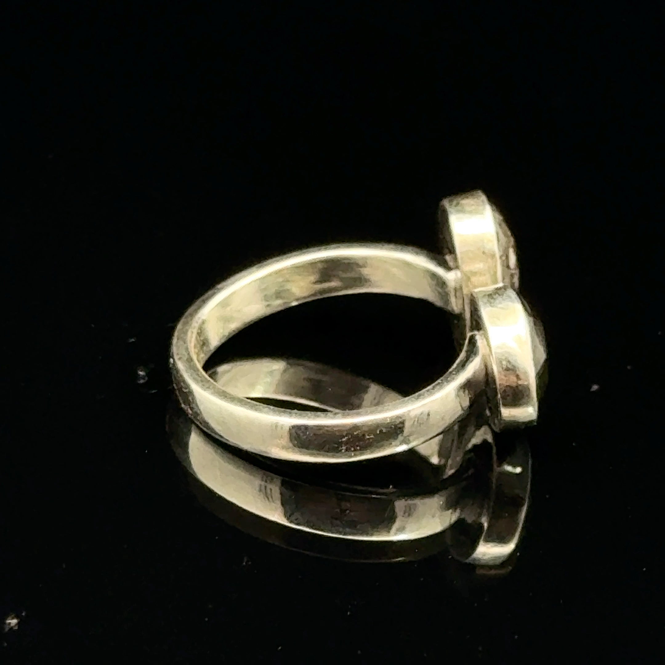 Detailed view of faceted Moldavite and Herkimer Diamond gemstones bezel-set in sterling silver, showing radiant green and clear crystal brilliance on a black background right side view. 
