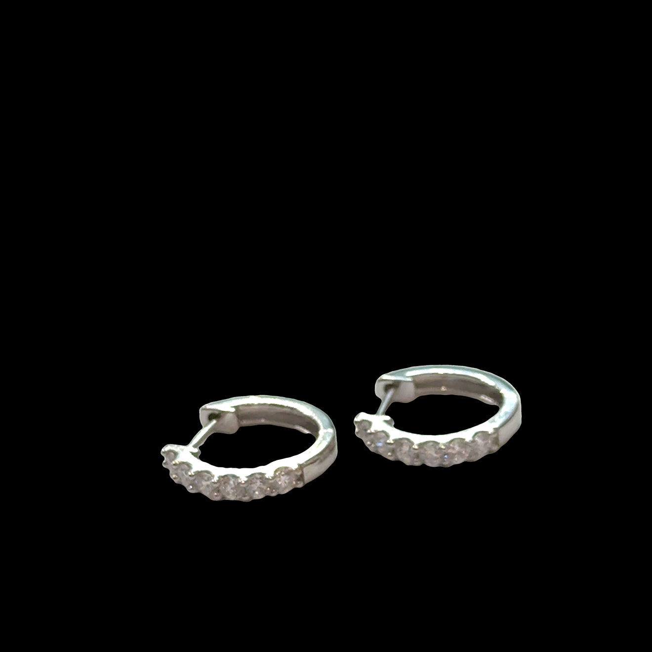 Diamond huggie hoops 925 silver with secure hinged closure, lab-grown diamonds, hypoallergenic everyday earrings, on a black background, front close up overview.