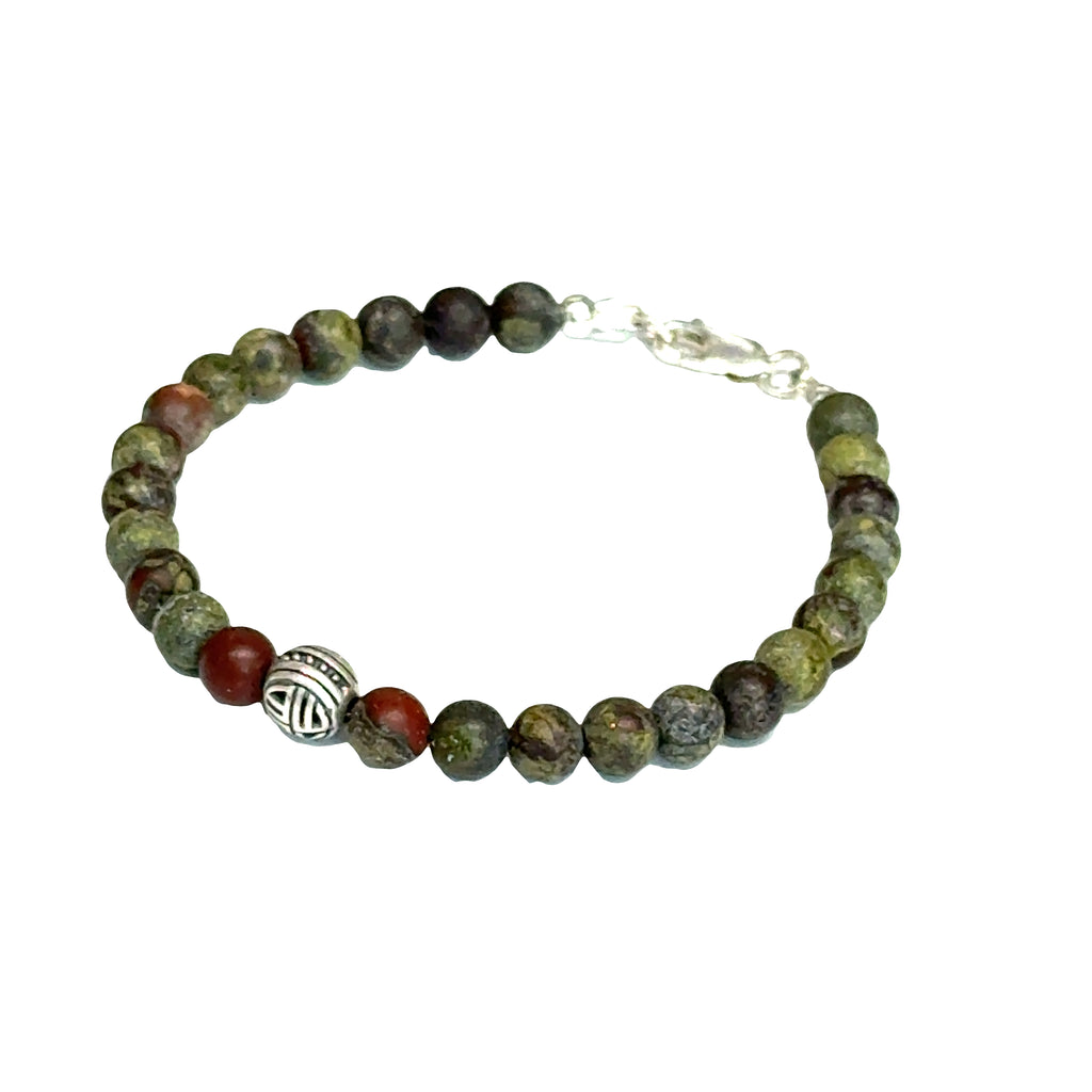 Dragon Blood Jasper gemstone beaded bracelet with sterling silver pattern bead and a lobster claw clasp showing red and green natural patterns  on a white background, left angle view. 