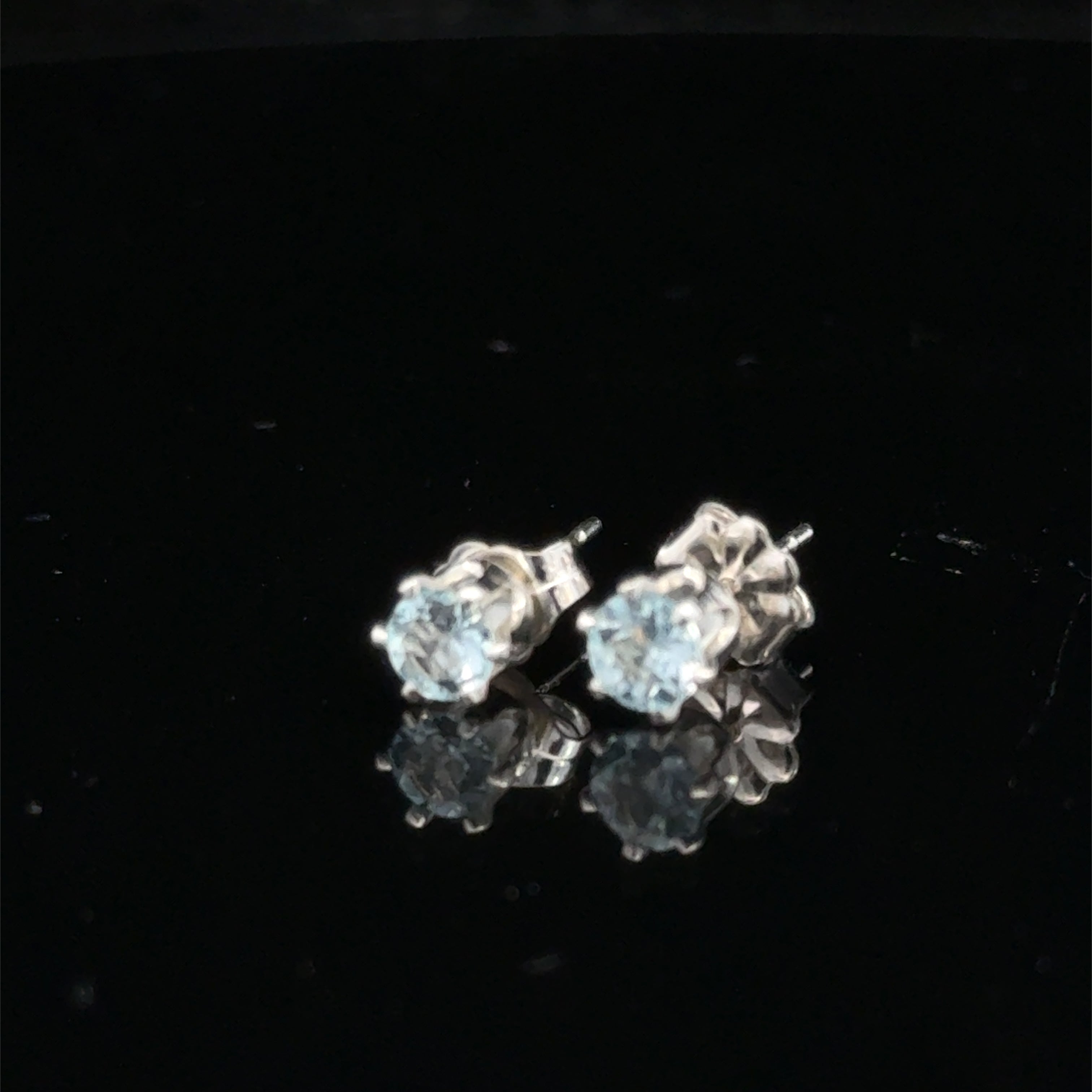 Elegant handmade Blue Topaz earrings for November birthstone gift on black background front slight left overview.