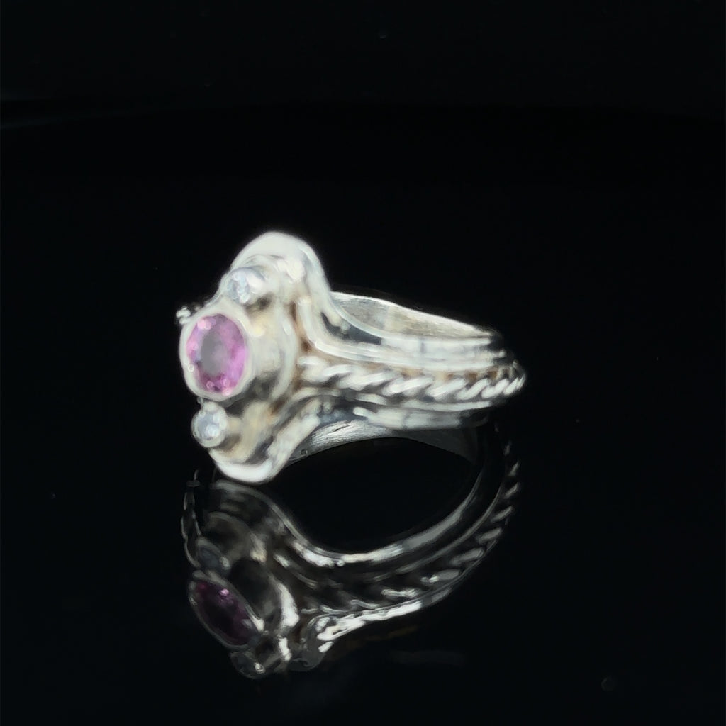 Elegant sterling silver step ring with Pink Sapphire focal stone and diamond accents on black left angle view