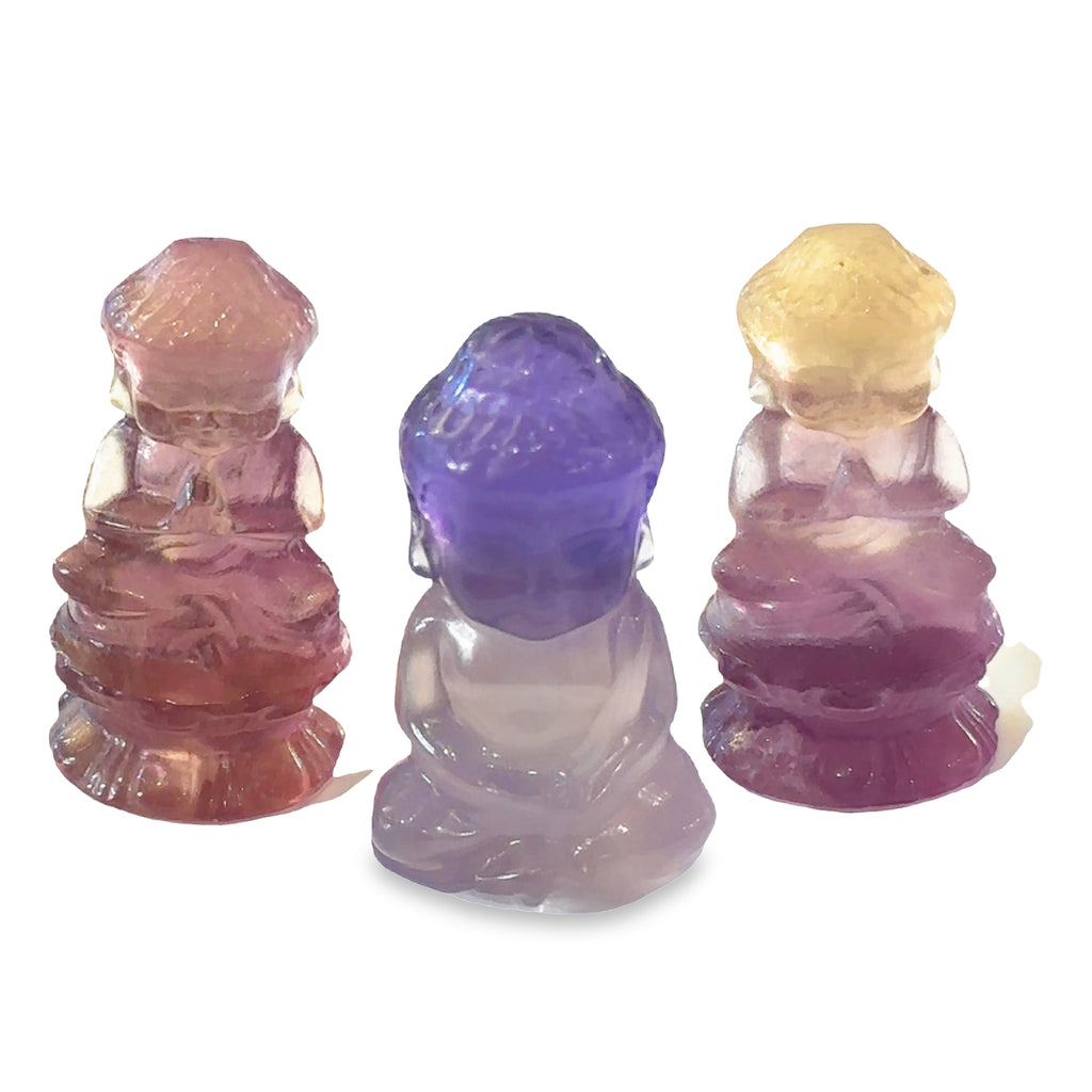 Ethically sourced fluorite gemstone Buddha carving with purple and yellow hues grouping on white front view