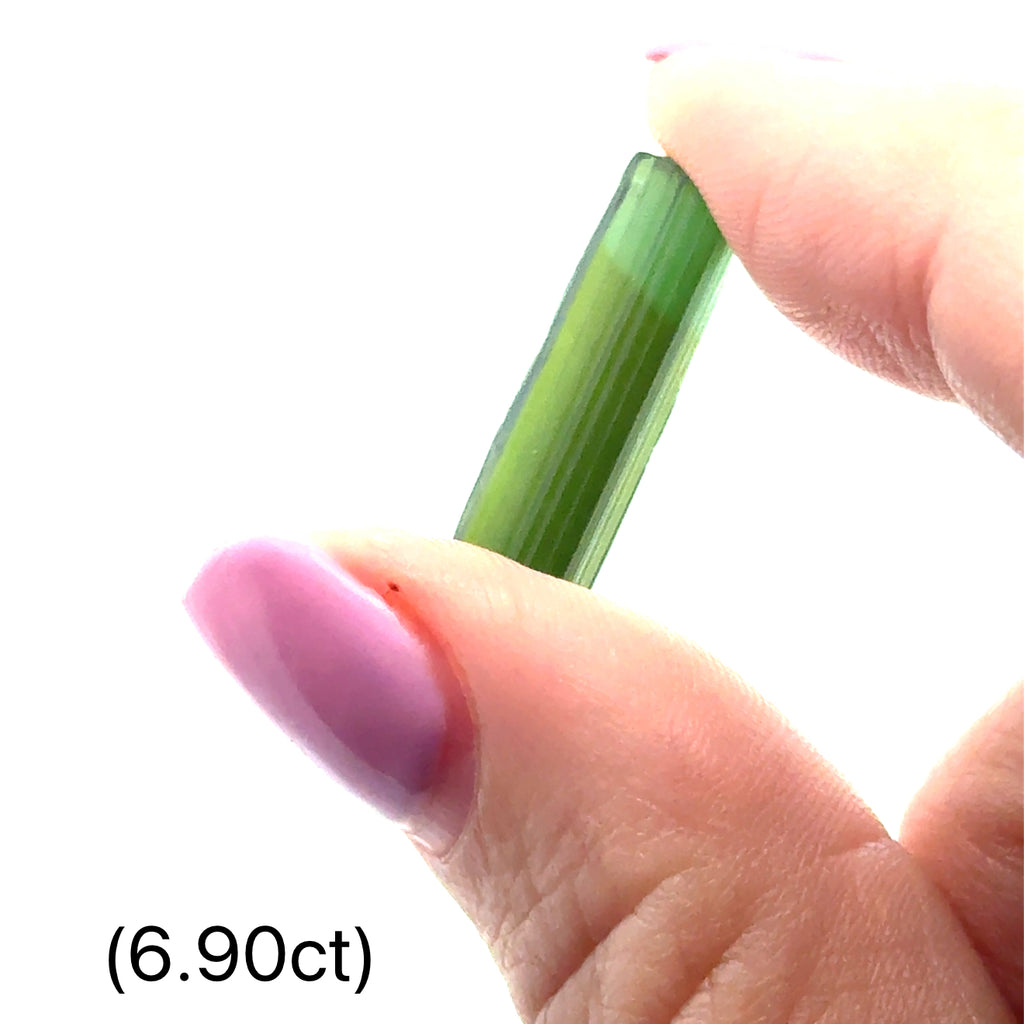 Ethically sourced raw Green Tourmaline gemstone with natural green hues (6.90ct) on white and in finger tips front view