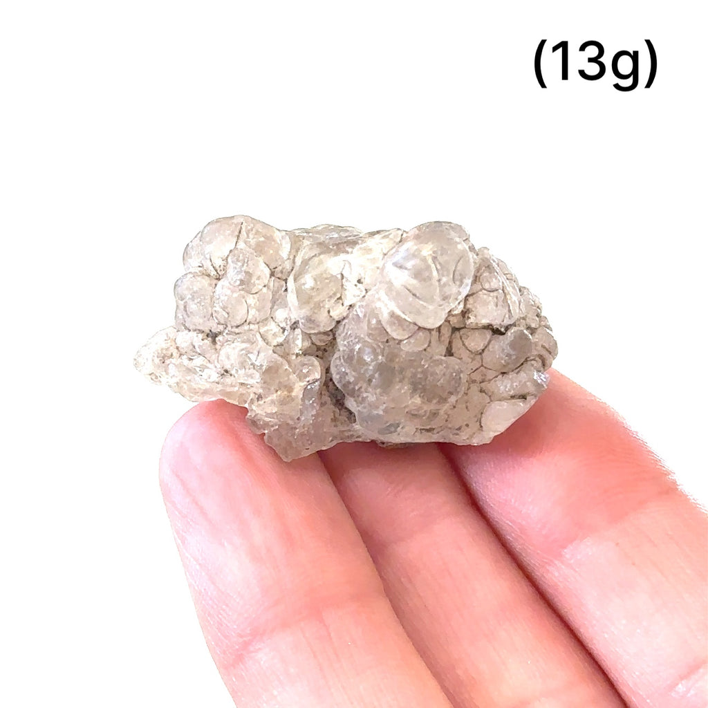 Ethically sourced raw Hyalite Opal gemstone with luminous glow grouping of (13g) on white in hand for overview