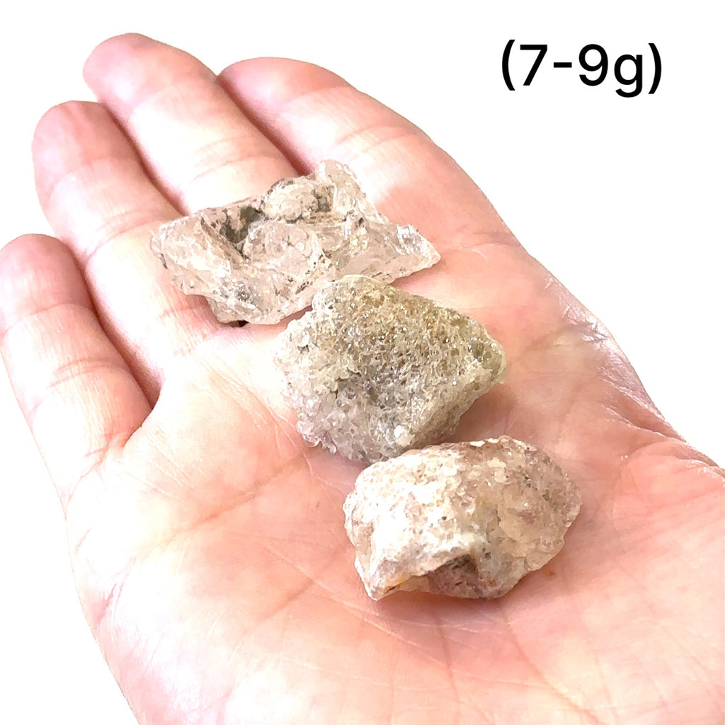 Ethically sourced raw Hyalite Opal gemstone with luminous glow grouping of (7-9g) on white in hand for overview