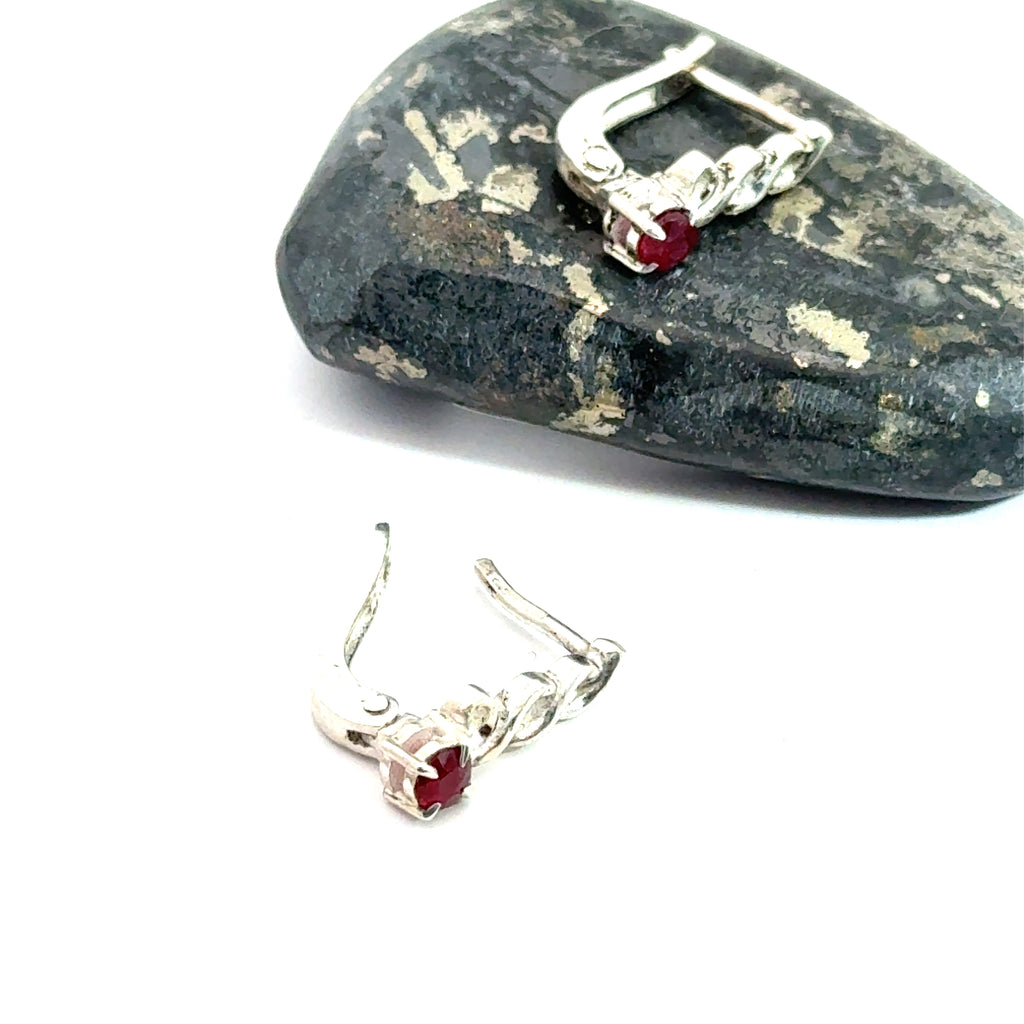 Faceted Ruby Snap‑Back Earrings on white and rock long side view