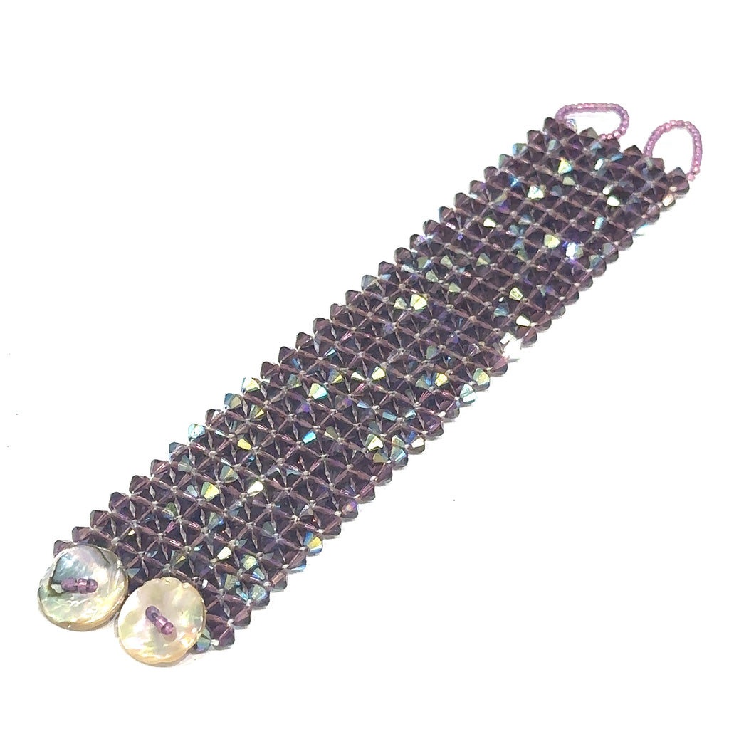Glitzy purple crystal cuff bracelet with seed bead hoop closure on white flat angle view