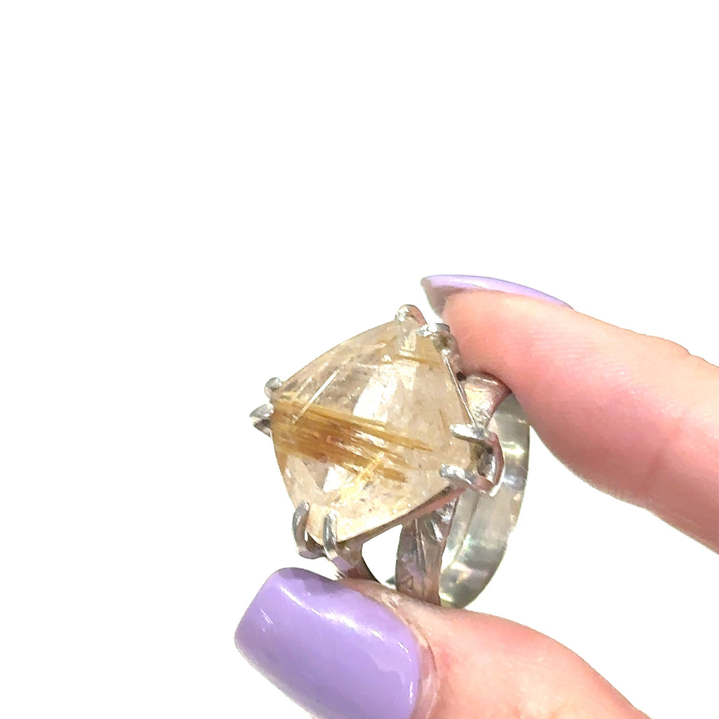Golden Rutile gemstone ring in sterling silver with faceted square quartz stone, size 7.5 side view on white in finger tips.
