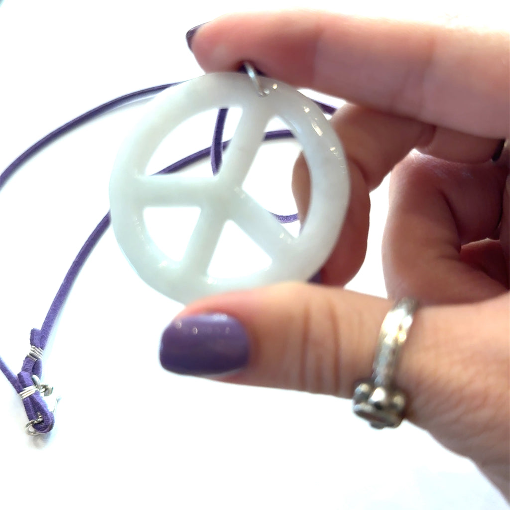 Green Jade Peace Symbol Pendant Necklace on white in hand center overview