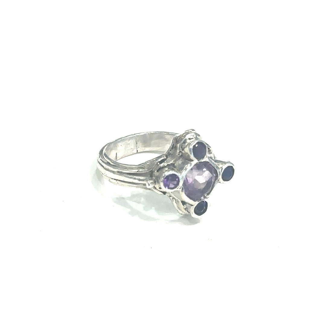 Hand‑forged sterling silver ring with 8mm faceted light Amethyst and four darker accent stones, size 7 on white slight right angle view