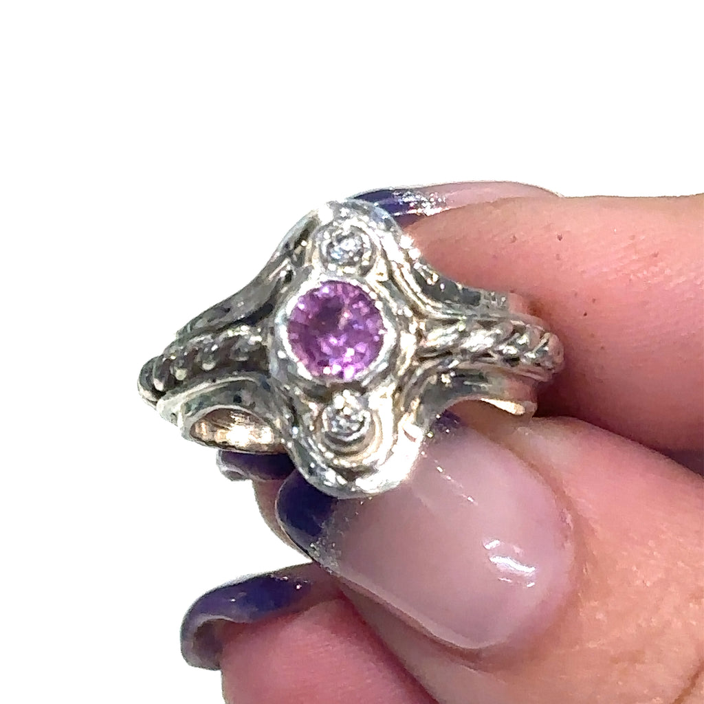 Hand‑forged sterling silver step ring with 5.4mm Pink Sapphire and two bezel‑set diamonds, size 7.5 on white in hand for a close-up view