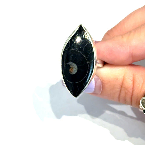 Hand holding a black and silver ring with a unique design on a white background, front view. 
