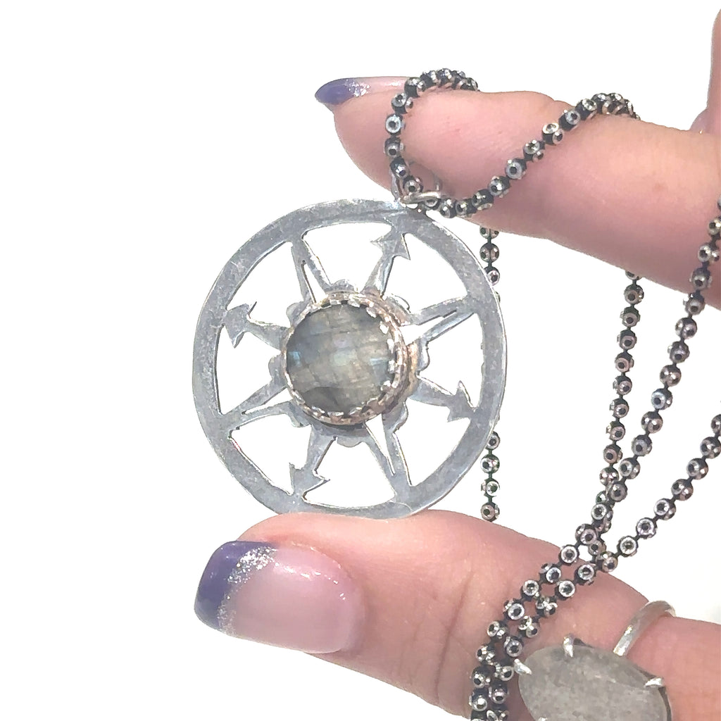 Handcrafted Labradorite compass pendant necklace with sterling silver bezel setting and oxidized 18'' chain on white in hand for close up view